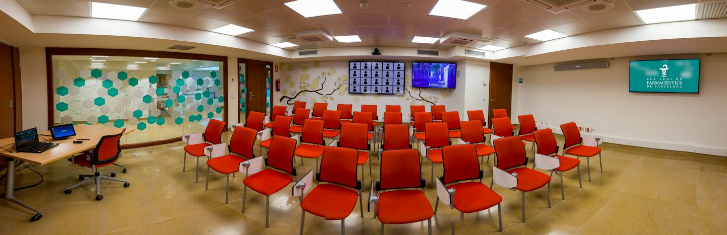 Sala de conferencias moderna con sillas y pantallas de presentación.